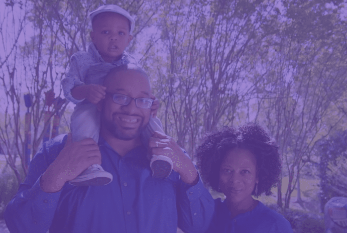 A father and mother smiling with a toddler sitting on the dad's shoulders