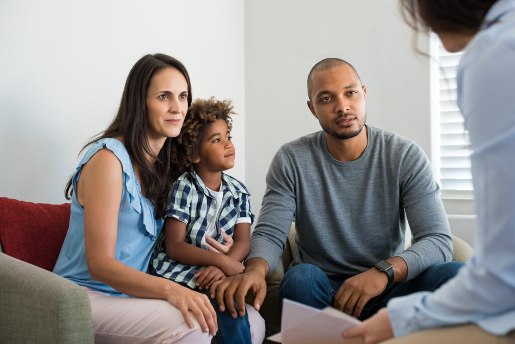 A couple with their adopted son talking to a counselor