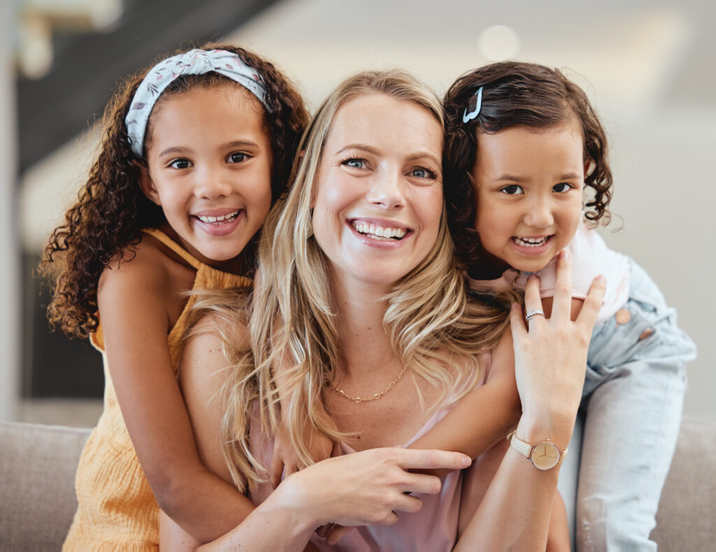 A happy lady being embraced by two little girls