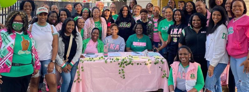 A group photo of a sorority gathering in front of a donation station