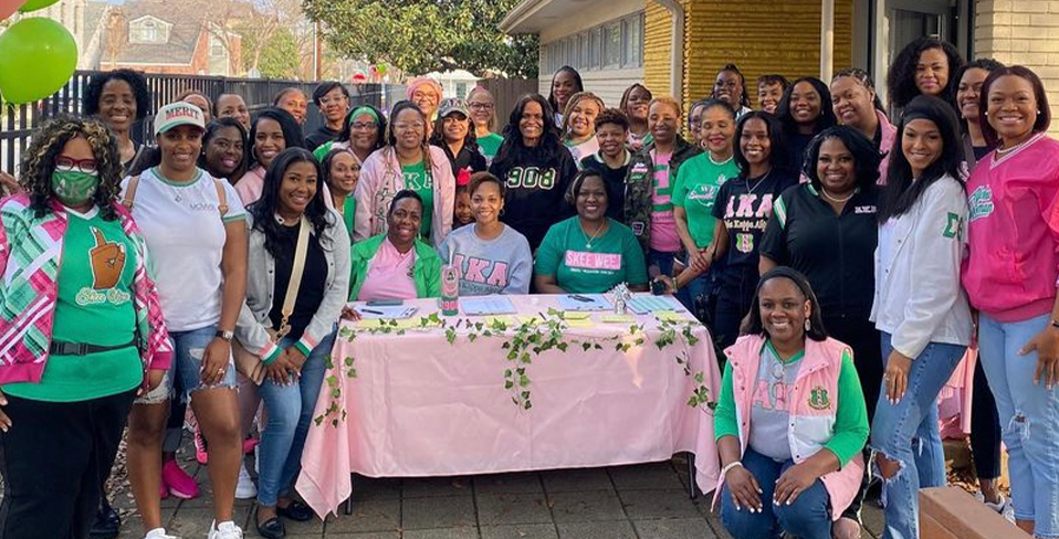 A group photo of a sorority gathering in front of a donation station