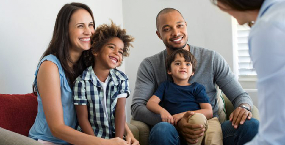 A couple with their adopted sons talking to a counselor