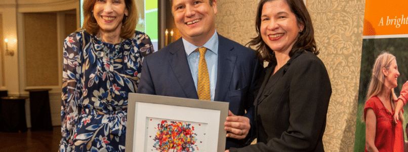 A man and two women holding a framed art piece