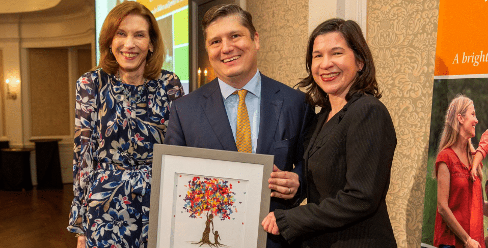 A man and two women holding a framed art piece