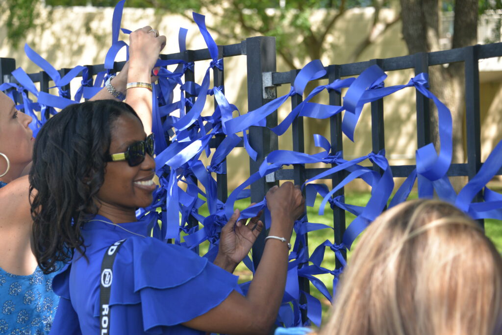 A couple of ladies hanging blue ribbons on a fence