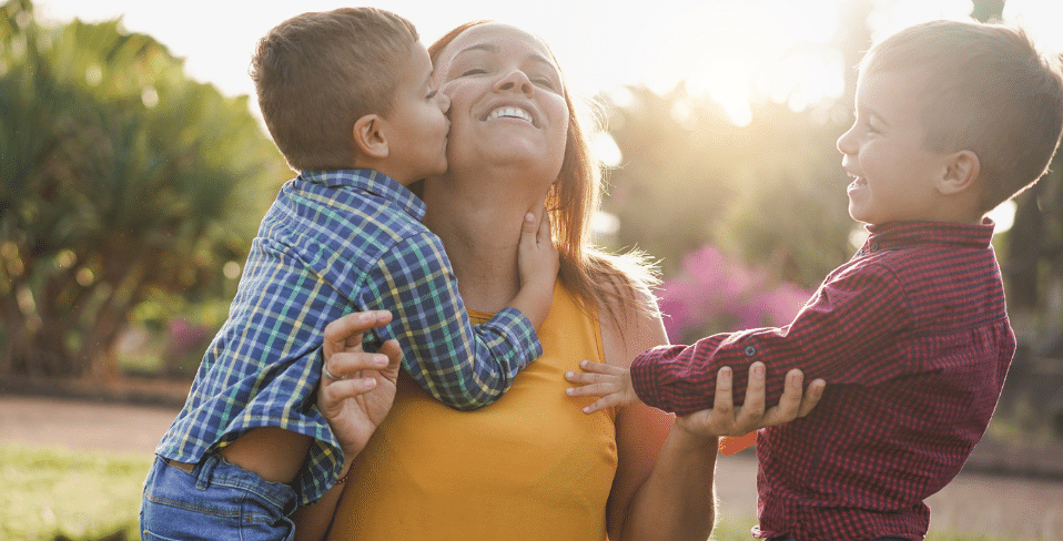 A lady being hugged and kissed by two little boys